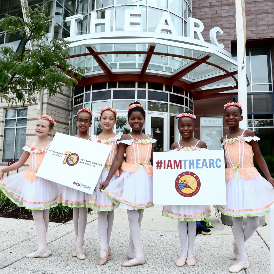 A group of young dancers holding signs in front of a theater.