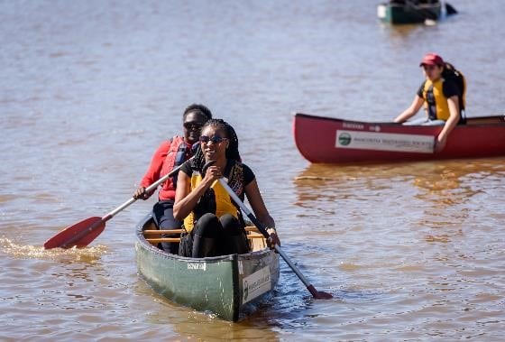 A group of people paddling in a canoe on a lake.