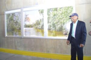 Two men standing in front of a wall with pictures of a river.