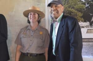 A man in a hat and a woman in a suit stand next to each other.