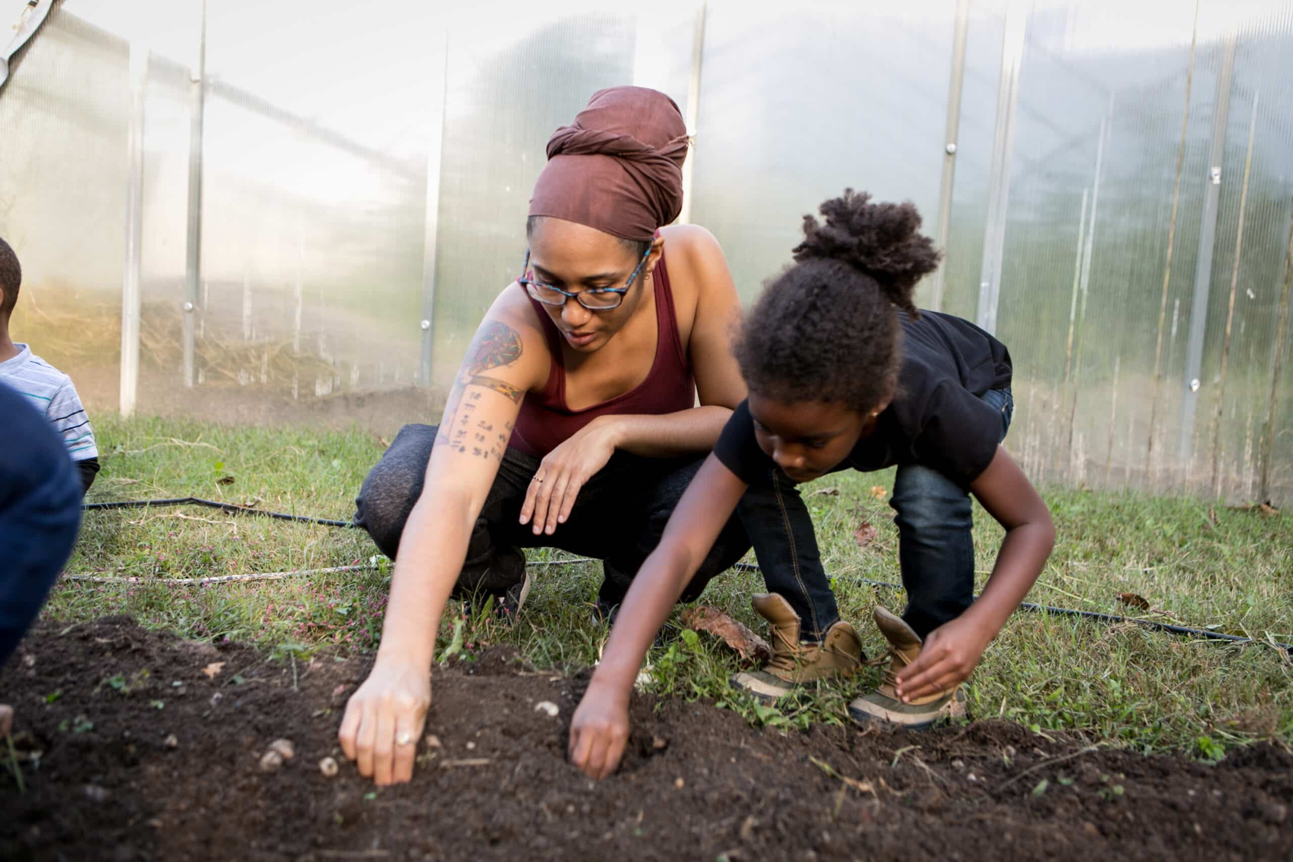A woman and children are planting in a garden.