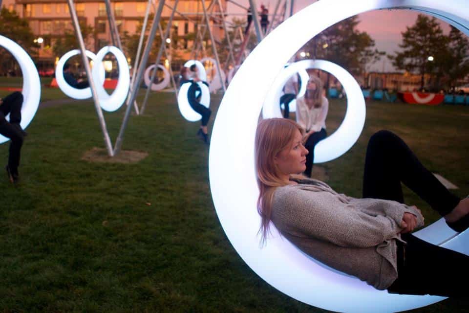 A woman sits in a circle of light sculptures.