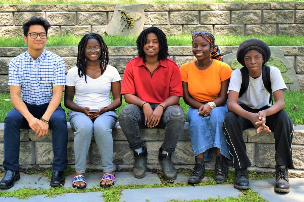 A group of young people sitting on a stone wall.