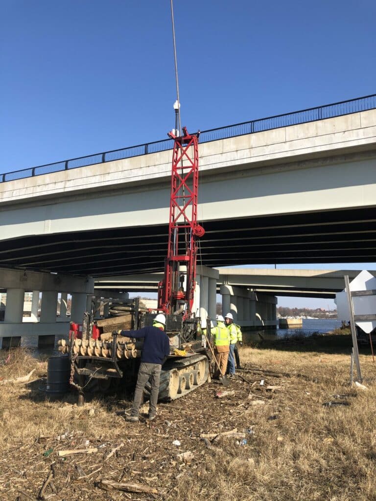 A construction crew is working on a road under an overpass.