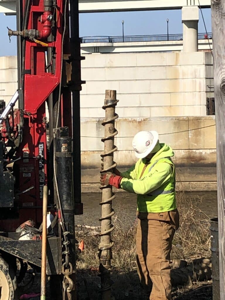 A worker is drilling a hole in the ground.