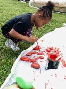 A little girl painting on a large canvas at Bridge Park Plots, cultivating urban farms and gardens for community growth.