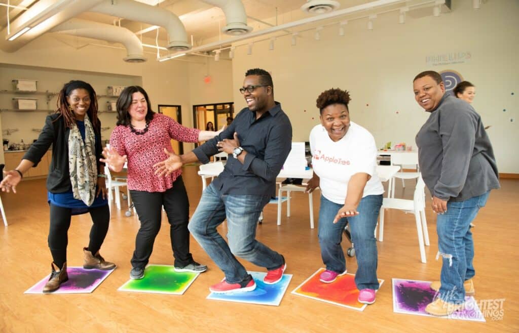 A group of people standing on colorful mats in THEARC office.