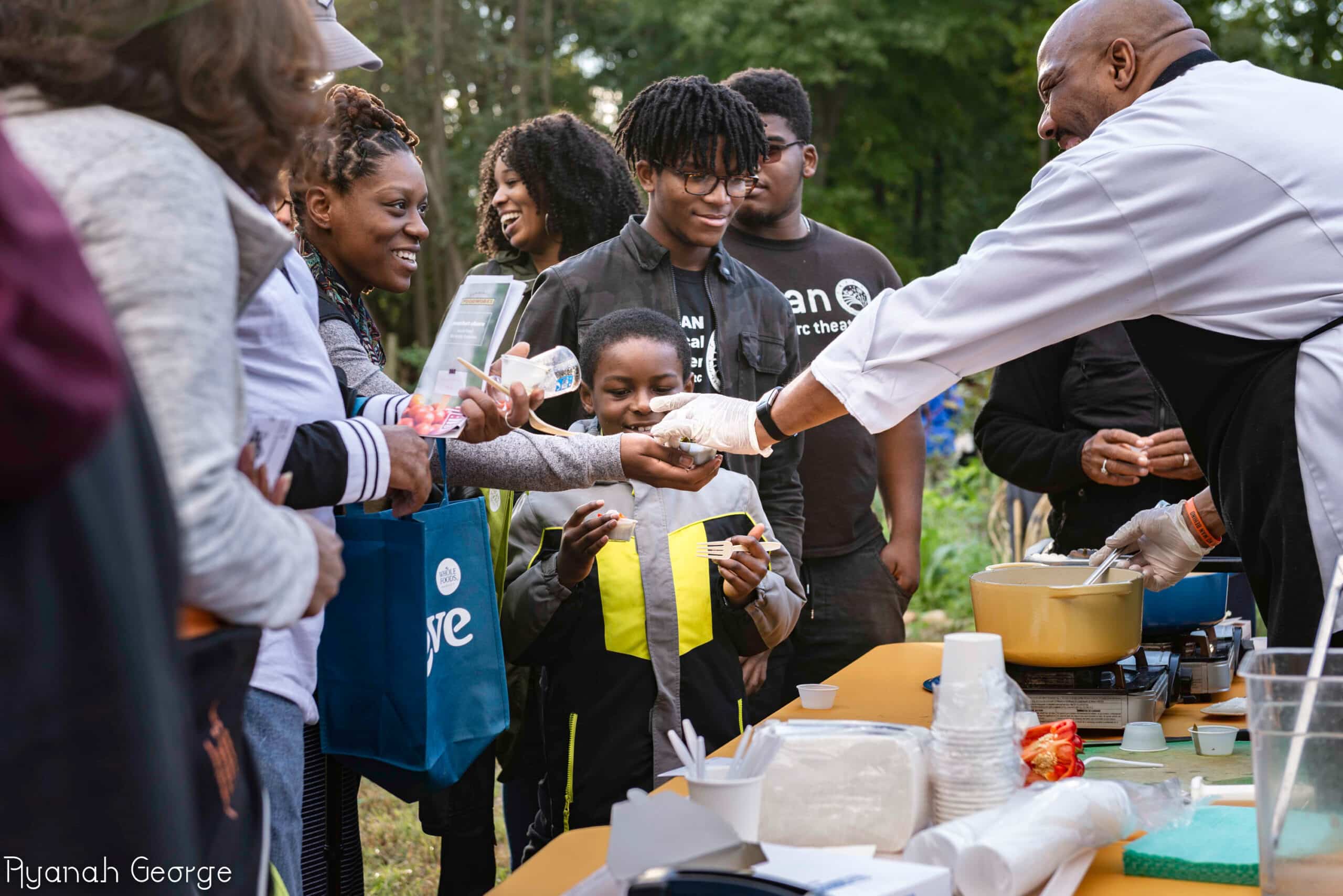 Community Events hosted by Building Bridges Across The River gather a group of people standing around a table with food.