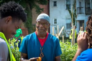 A group of people in Bridge Park Plots, cultivating urban farms and gardens, talking to each other for community growth.