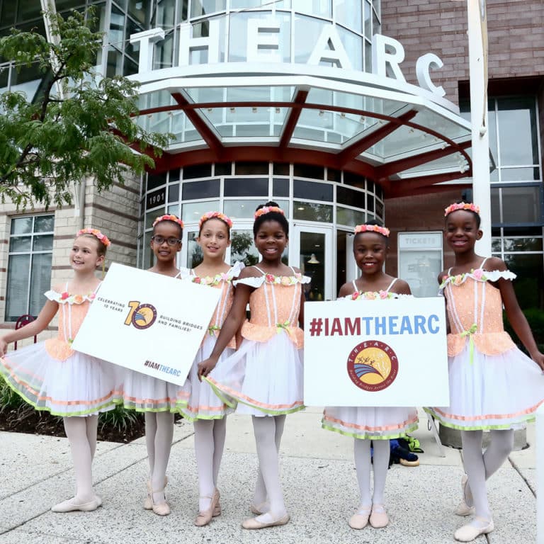A group of young dancers holding signs in front of THEARC, the largest nonprofit collaboration hub in the country.