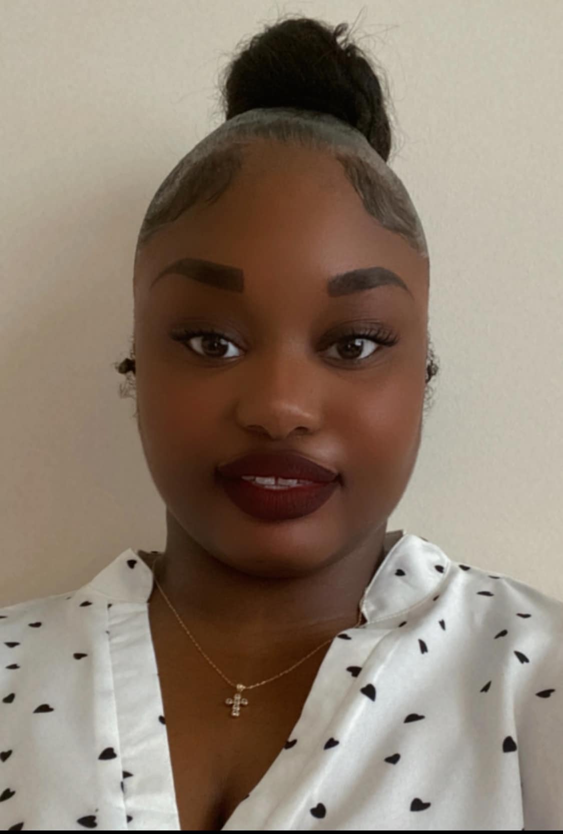 A woman with a high bun hairstyle and a white blouse with black polka dots is facing the camera, wearing a cross necklace, embodying the essence of building a better future.