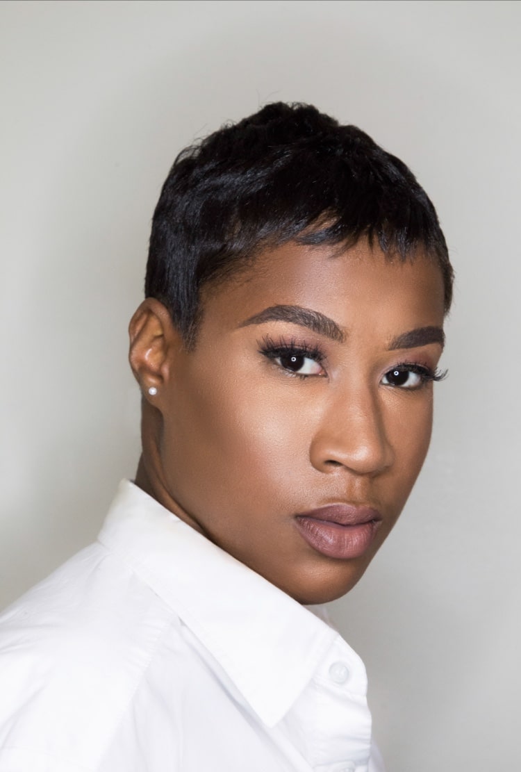 A person with short hair and expressive eyes is wearing a white collared shirt, looking directly at the camera, embodying a vision of building a better future.