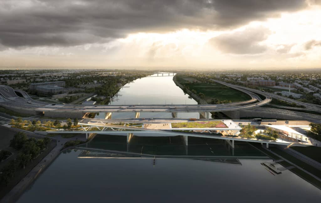 Aerial view of a bridge over a river, embodying the essence of "Building Bridges Across The River - Our Story." It's surrounded by roads and lush greenery under a cloudy sky, with sunlight breaking through—a testament to community-driven design.