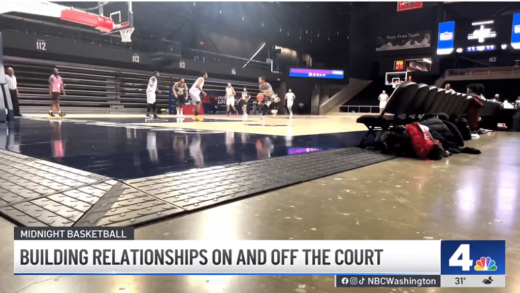 Basketball players on an indoor court during a game with viewers watching; a news banner reads "Building Relationships On and Off the Court.