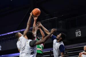 Basketball players reach for the ball during a game.